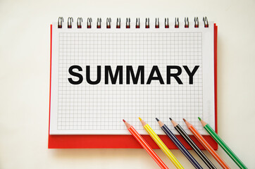  a summary of the word written on a notebook with pencils. a summary of the material.