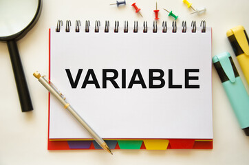 text The variable is written in a notepad. Variable universal life insurance. the text is written on a white piece of paper. in the lens of a calculator and pens
