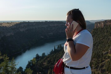 girl calling by cell phone at the top of the Duratón river canyon in Segovia Spain