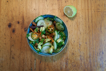fried chickpeas with avocado, cucumber, paprika, carrots parsley in a blue bowl on a rustic wooden table