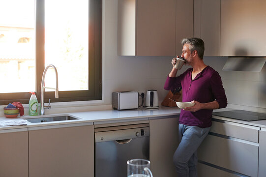 Man having breakfast in his kitchen - Powered by Adobe