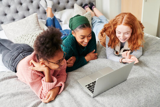 Teen girls lying on a bed with a laptop