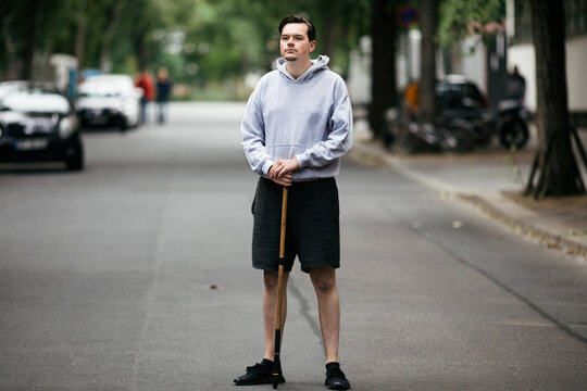 Young Man In Hoodie Holding Wooden Stick in Street