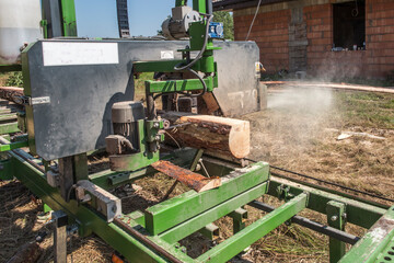 Fototapeta na wymiar Mobile sawing equipment for logs in the open air. Mobility and work speed