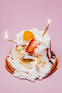 creamy birthday cake destroyed and golden candle
