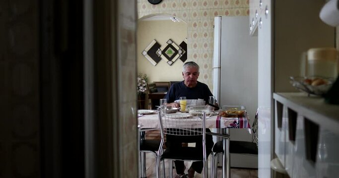 Lonely older man eating lunch alone in home kitchen
