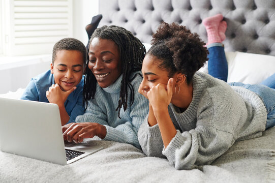 Mom and daughters using a laptop together - Powered by Adobe