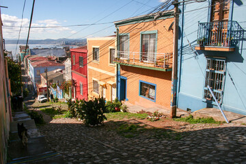 Fototapeta na wymiar Pedestrian hilly street of Valparaiso with colorful houses and top view on city and ocean in sunny day