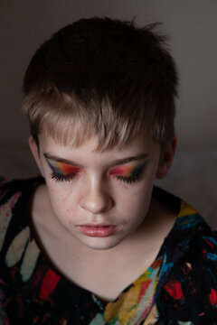Boy in a dress wearing bright make up.
