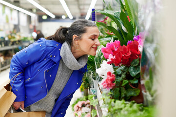 Smiling woman smelling flowers in market