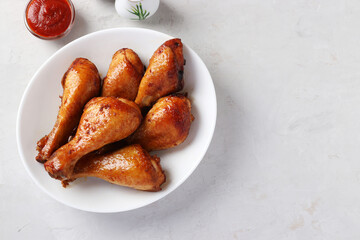 Roasted chicken drumsticks in honey and soy sauce on white plate, view from above, with space for text