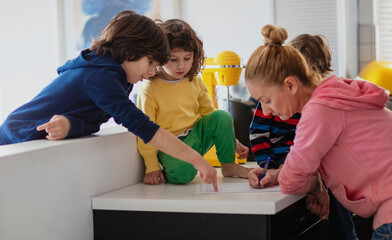 Young woman creating a shopping list for grocery with some suggestions from her kids...
