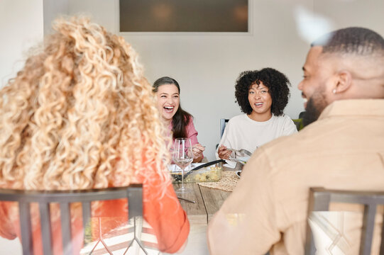 Laughing friends having dinner at home