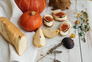 pumpkins, baguette with ricotta and figs on a white table. Vegan, vegetarian, healthy, comfort food concept. Autumn still-life. Halloween. Harvest. Postcard