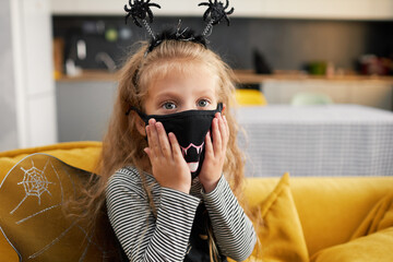 Funny child girl dressed in witch canival costume. Halloween holiday during quarantine time