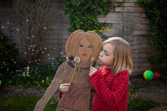 Blowing dandelion clocks with a pretend cardboard friend.
