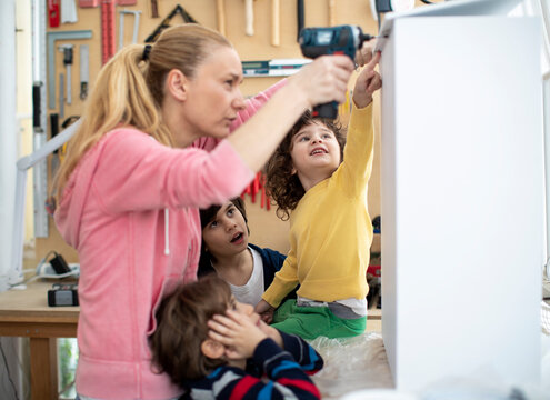Mother with her kids using an electric screwdriver