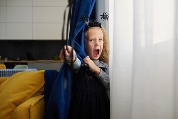 Funny child girl dressed in witch canival costume. Halloween holiday during quarantine time. Home patry