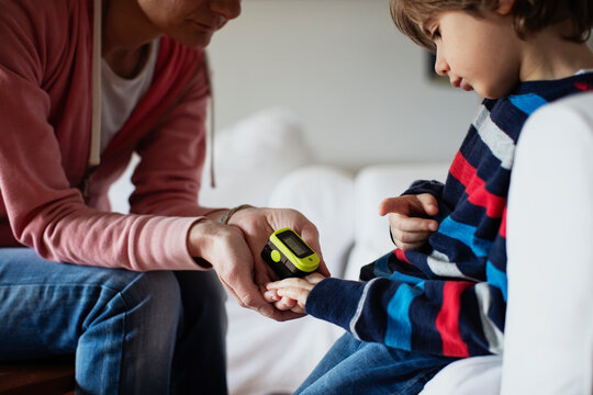Mother measuring the oxygen with pulse oximeter to her kid
