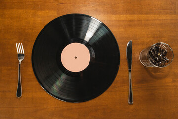 Vinyl record, spoon and fork and audio cassette tape in a glass