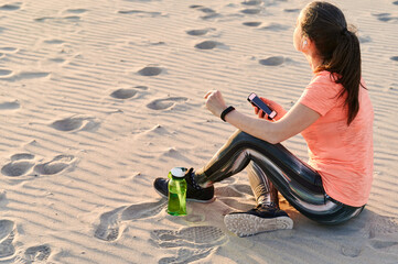 Fit woman sitting on a beach after a run