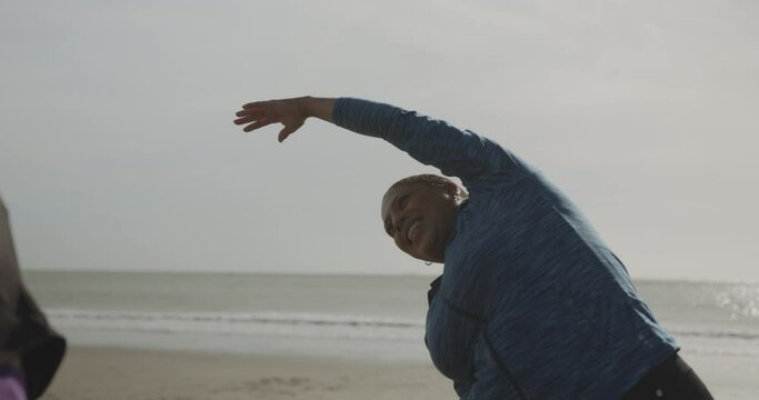 Two plus size females exercising stretching outdoors on beach, Obese black women sports training body positive
