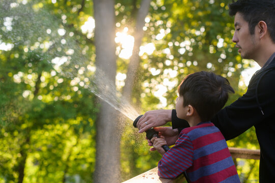 Dad And Child Watering The Grass