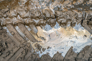Close-up of a fresh tractor track in the mud. The photo was taken in the autumn season on a Dutch forest path immediately after a tractor had driven past.