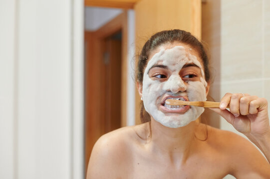 Woman brushing her teeth in a mirror