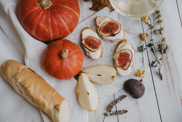 pumpkins, baguette with ricotta and figs on a white table. Vegan, vegetarian, healthy, comfort food concept. Autumn still-life. Halloween. Harvest. Postcard