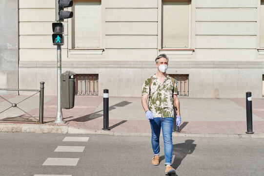 Man in a face mask crossing a street