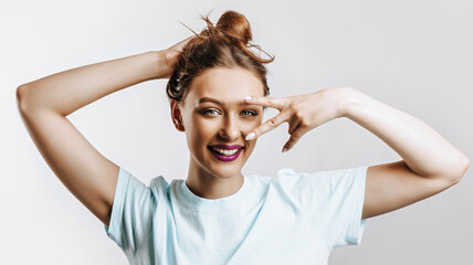 A beautiful young brunette girl holds her hair and makes her own hairstyle. The woman with purple...