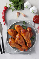 Roasted chicken drumsticks in honey and soy sauce on grey plate, top view. Vertical format.
