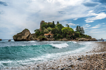 Fototapeta na wymiar Wunderschöner steiniger Strand mit türkisblauem Wasser und großen Wellen vor der Isola Bella auf Sizilien