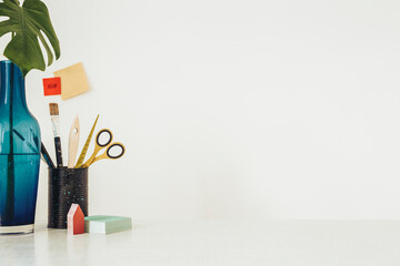  Artist desk with brushes, tools and flower - workspace. with white wall background.