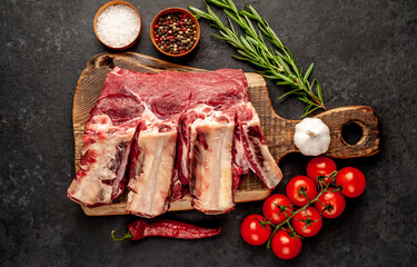 raw beef on the bone with spices on a stone background