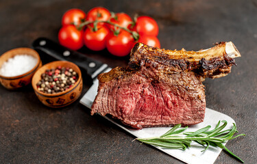 Baked beef on the bone with spices on a meat knife against a stone background