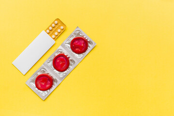 Composition with colorful condoms and birth control pills on yellow background. Safe sex and...