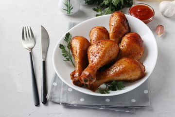 Baked chicken drumsticks in honey and soy sauce on white plate with parsley. Closeup. Horizontal format.