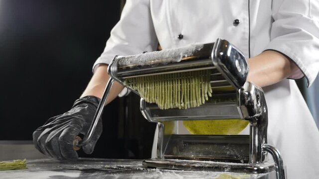 Traditional Italian cuisine. making pasta on machine for cutting pasta. Slow motion. Dough slicing machine. pasta making machine to make fresh spinage tagliatelle. Full hd