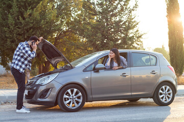 road trip, transport, travel and people concept - family couple with open hood of broken car at...
