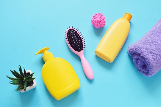 Flat lay beauty photography bath products, toiletries essentials set. Liquid soap, natural shampoo in a yellow package, purple towel on a blue background