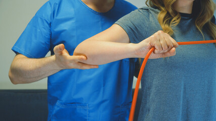 Physical therapist helping to do exercise with resistance bands. Medical homecare.