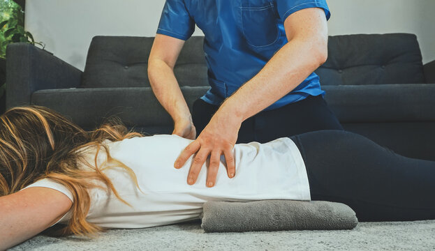 Therapist massaging woman's back at her house. Medical homecare.