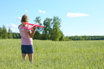 happy child plays with plane in the field