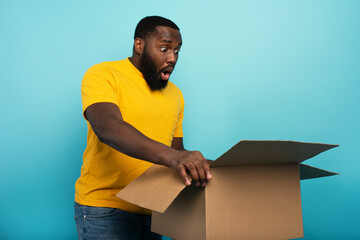 Happy boy receives a package from online shop order. happy and surprised expression. Blue...