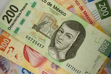 Mexican pesos bills spread randomly over a flat surface