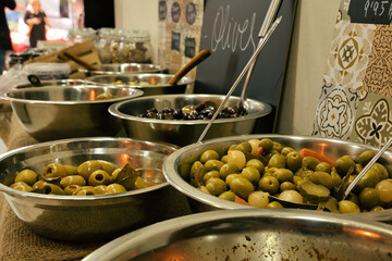Bowls of different olives on a wooden table in a typical shop in Barcelona