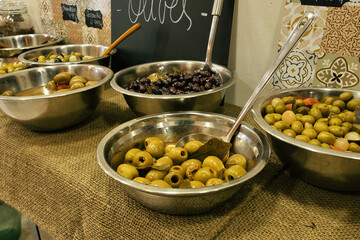 Bowls of different olives on a wooden table in a typical shop in Barcelona