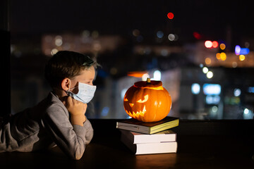 Sad boy celebrating halloween alone social distance. A child in a mask on the eve of all saints day. Kid in a protective medical mask. Covid-19 coronavirus pandemic 2020. treat or trick  no party